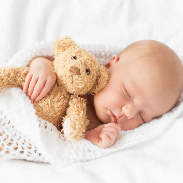 A baby sleeping with a teddy bear