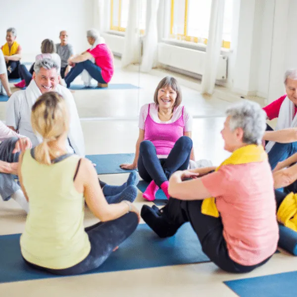 A group of men and women sat on yoga mats talking