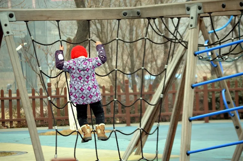 A child is climbing up a web