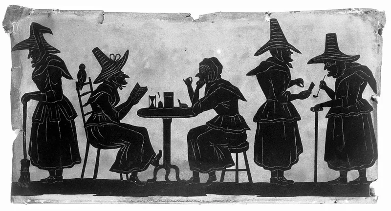 A black and white illustration of witches from the nineteenth century, 2 are sitting at a table in the centre of the image, 2 are standign talking to the right of the picture and 1 is standing holding a broomstick to the left of the picture