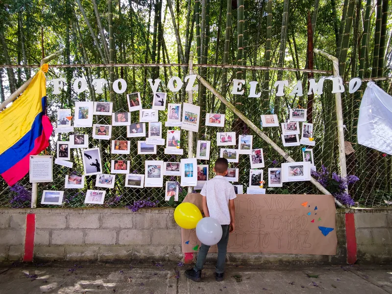Child stood in front of fence covered in photos