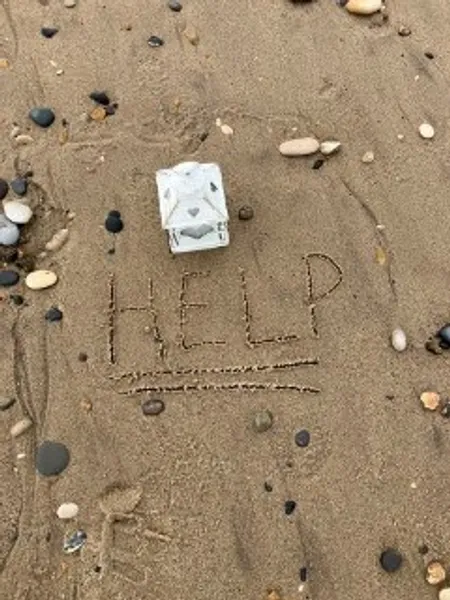 The word Help written in sand on a beach in Seaham