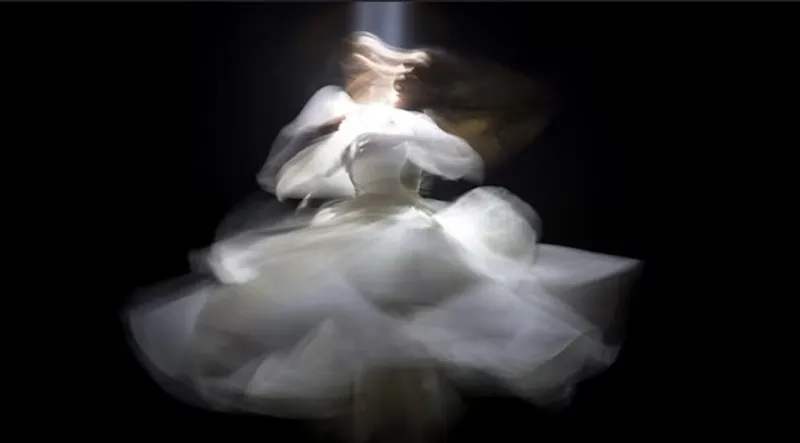 An artistically unfocussed photograph of a person dancing in a white dress