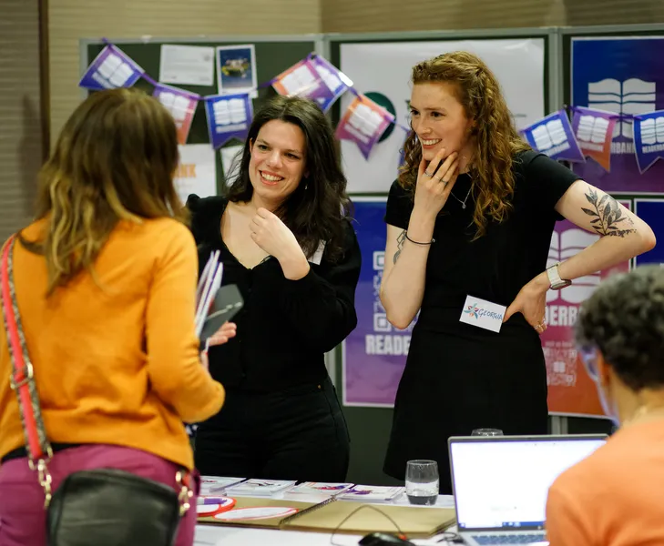 Two researchers smiling and explaining something at a booth