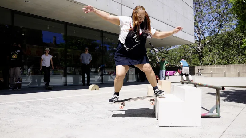 A person with long hair in two pigtails wearing a pinafore doing a trick on a skateboard/