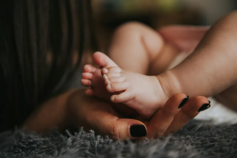 A close up of a child's feet in its mother's cupped hands