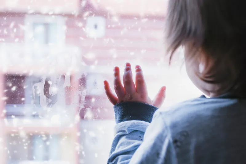 child at a window. iStock