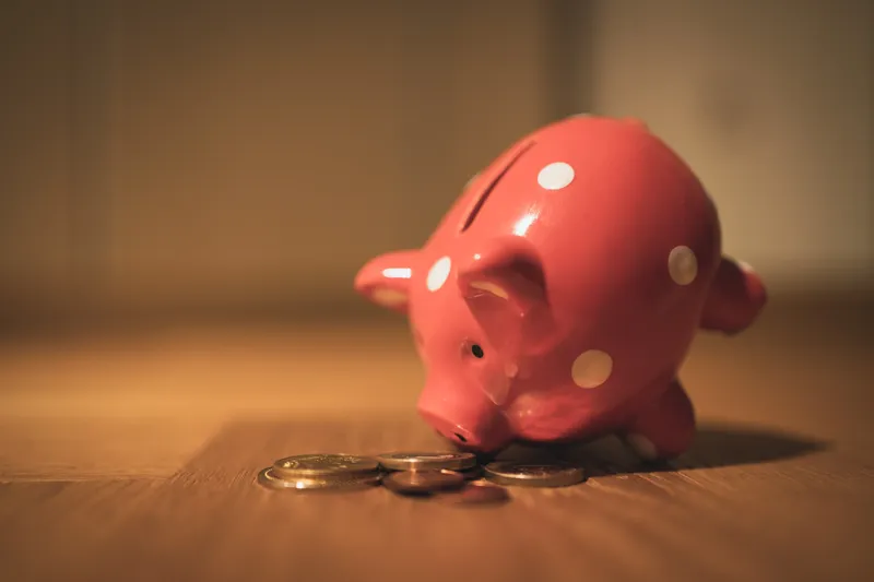 A piggy bank resting on the table, its nose pointed to coins