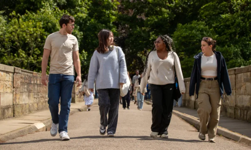 Four students walking across a bridge and talking