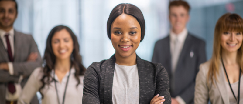 A female business student stands in front of other students smiling