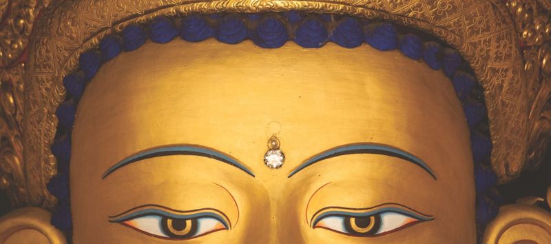 A close-up of the gold eyes of a statue of Buddha.