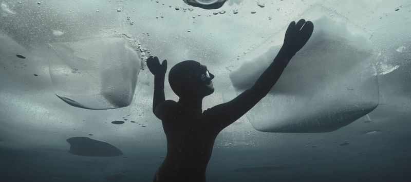 Still from Johanna (2016), courtesy of Ian Derry, showing a free-diver under ice reaches for the surface.