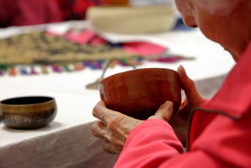 Lifelong learning group member taking part in a workshop handling museum objects.