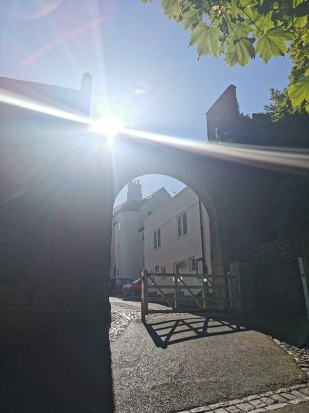 Archway to the Bailey with sunshine looking towards Cuth's