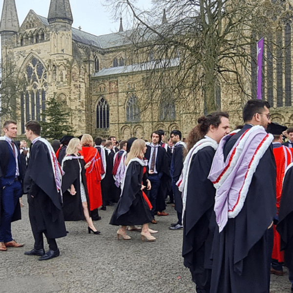 A group of students in gowns outside Durham Cathedral