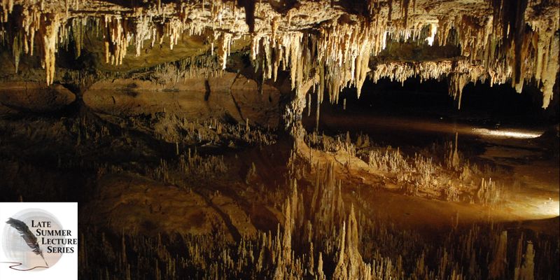 Stalactites and stalagmites in an underground cavern, with their sharp points reflected in water