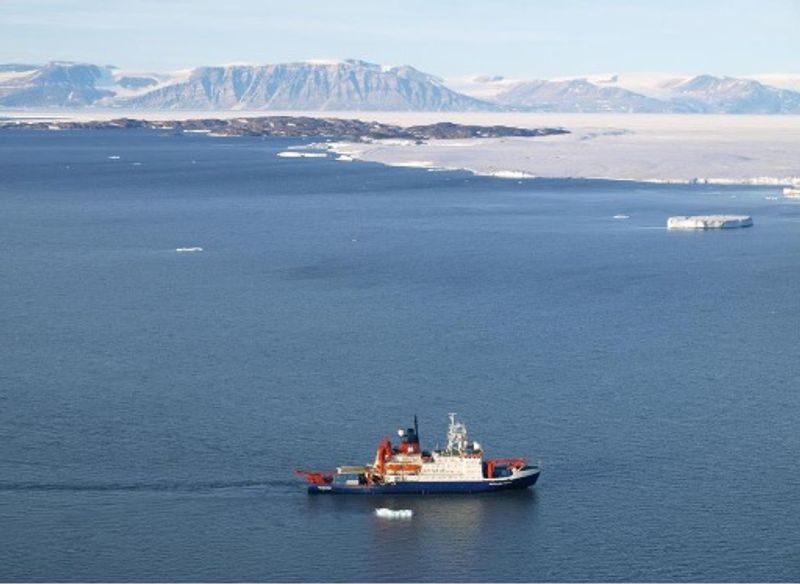 A boat in water with greenland in the distance