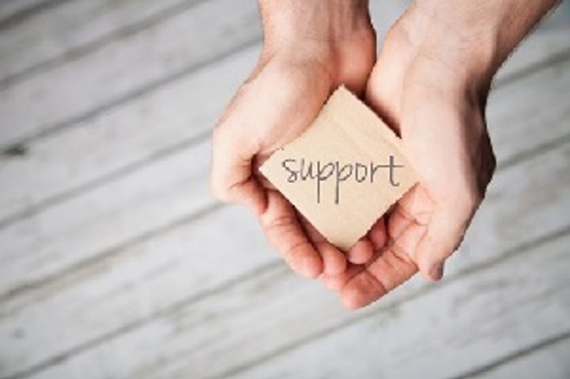 Hands with a piece of paper saying support