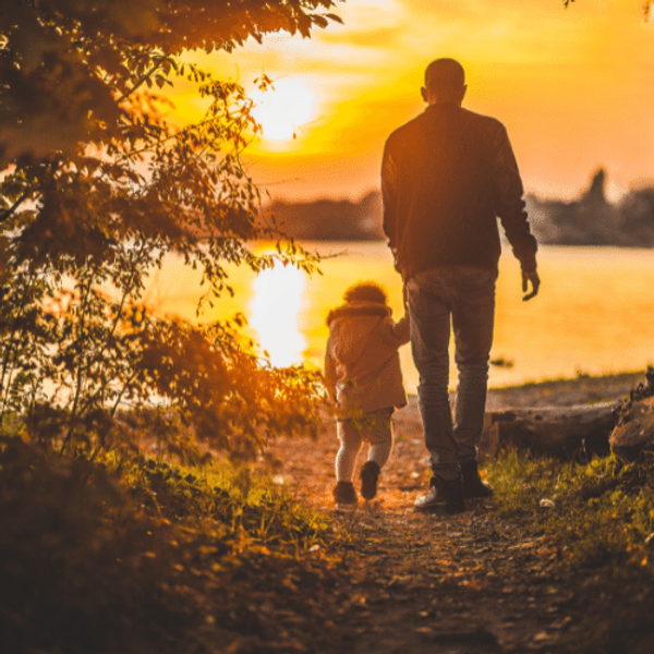 Man walking with a child into the sunset
