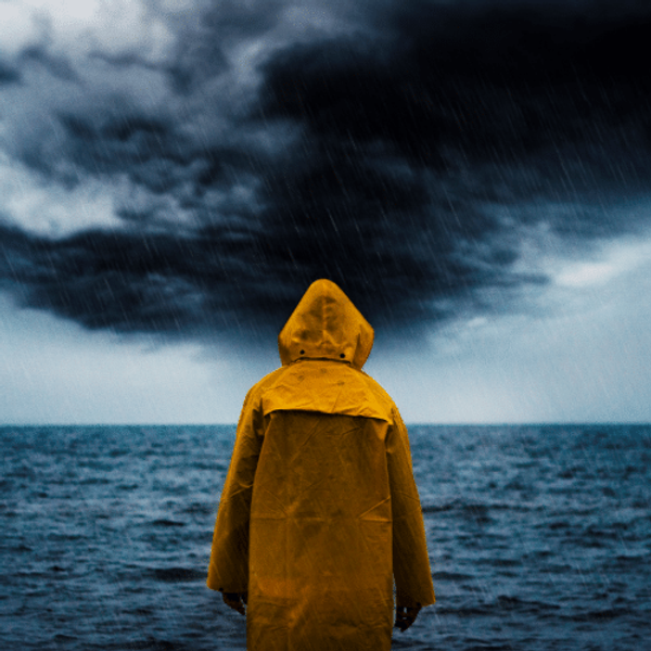 Man in a yellow anorak watching a storm out to sea