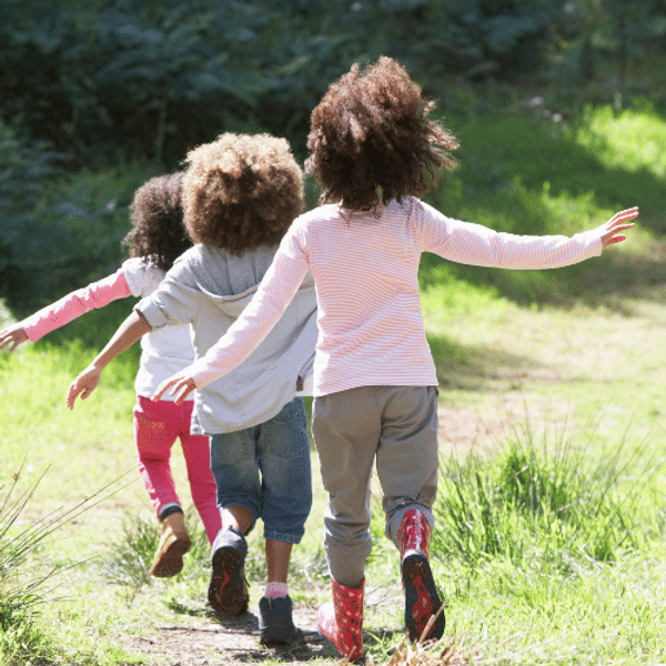 Three young children from behind with their arms stretched to the sides