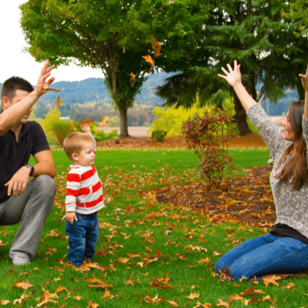 Family in the park with hands in the air crouching among leaves