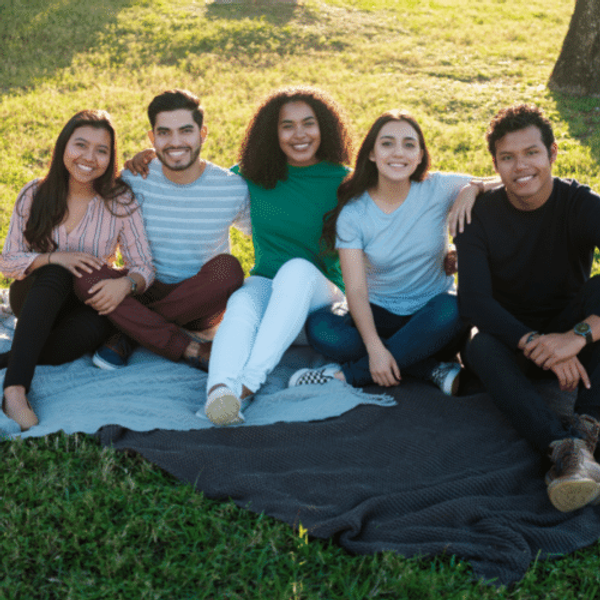 Group of friends sat on a rug in the park
