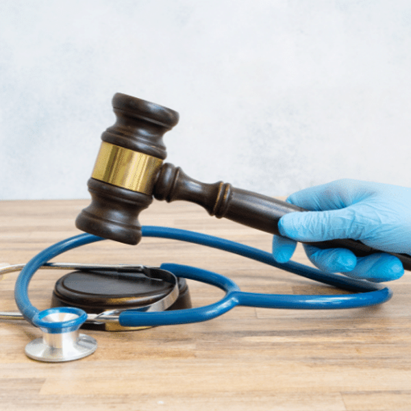 A stethoscope and gavel held by a gloved hand