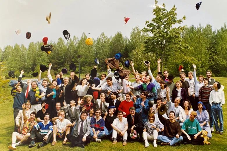 group of students outside in summer throwing hats up in the air to celebrate