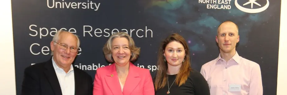 A group of people standing in front of a banner which says space research. They are smiling at the camera.