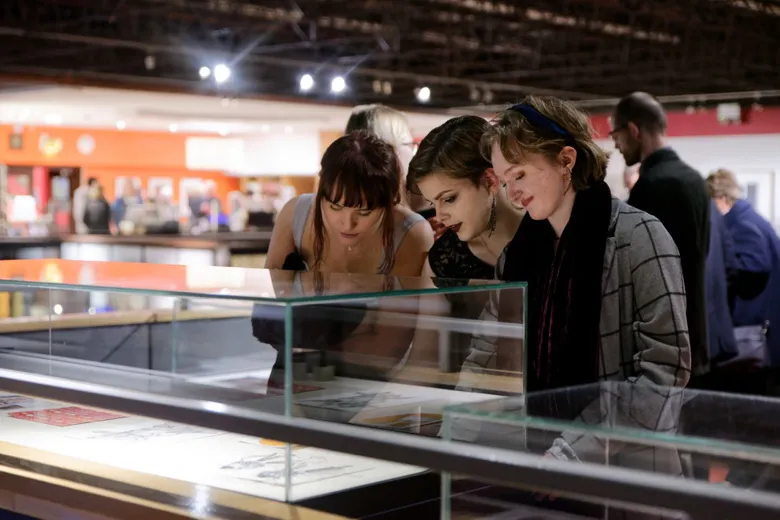 Three visitors to the exhibition exploring the display cabinets