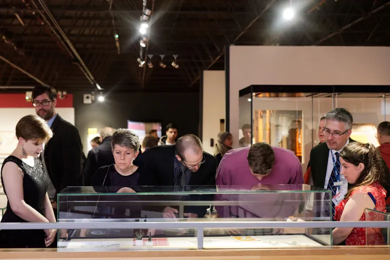 Five visitors to the exhibition exploring the display cabinets