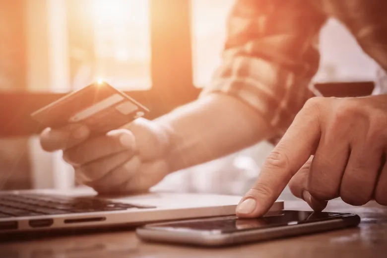 Man hands with a credit card, calculator and laptop.