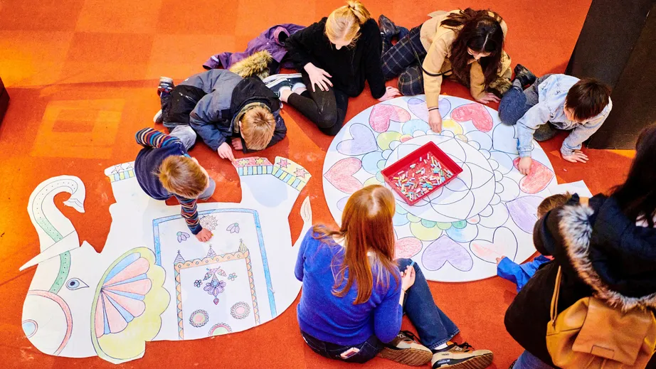 Student helping local children colour in designs as part of Holi Festival