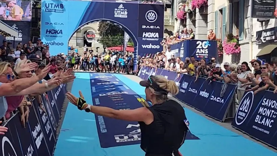 A women running away from the camera towards the finishing arch of the Ultra Trail de Mont Blanc ultramarathon
