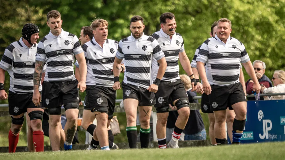 A group of male rugby players wearing black and white shirts walking in a line.