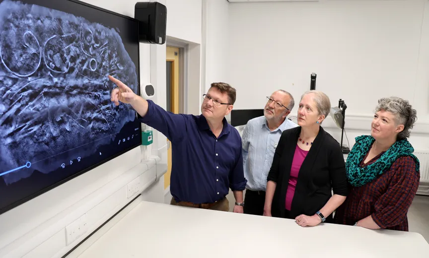Group of people looking at a CT scan, produced by MUVIS, University of Southampton, of the block of artefacts excavated from Melsonby. From left to right: Professor Tom Moore, Head of the Department of Archaeology, Dr Keith Emerick, Inspector of Ancient Monuments, Historic England, Dr Emily Williams, Department of Archaeology, and Dr Sophia Adams, Curator, The British Museum.