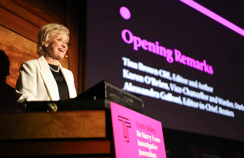 Woman smiling and speaking at lectern