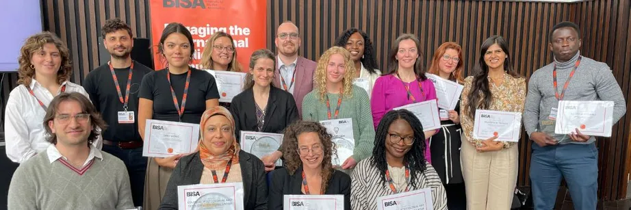 A group of people sitting and standing and looking at the camera. They are smiling and holding certificates.