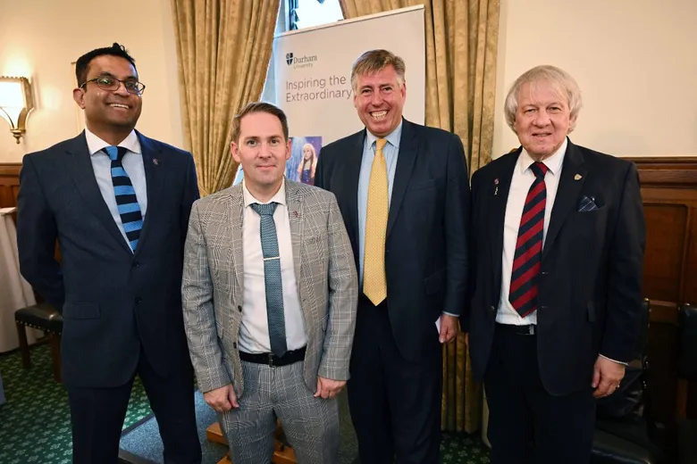 Four men in suits standing in front of a pull-up banner