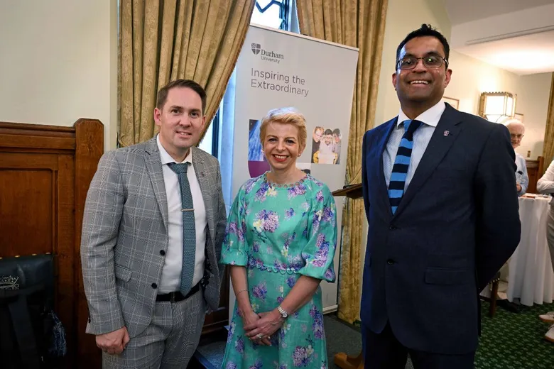 Two men and a woman standing in front of a pull-up banner