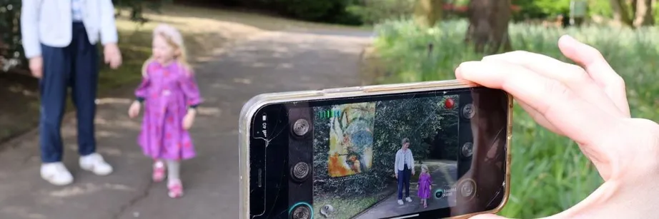 View through a mobile phone screen of a woman and child on a woodland path