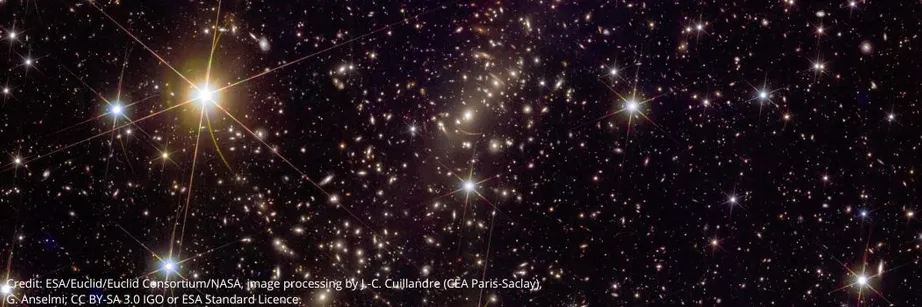A galaxy cluster showing bright galaxies against a black, starry backdrop