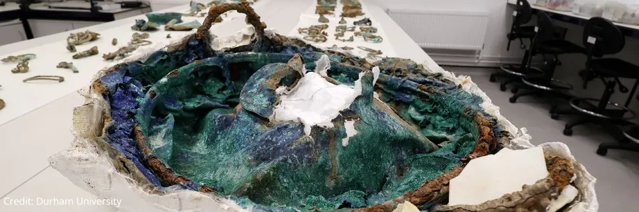 The cauldron from the Melsonby Hoard at the foreground of the picture with other objects behind.