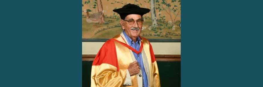 Hunter Davies wearing a black academic cap and red and gold robes smiling at the camera.