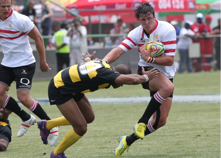 Rugby player being tackled on the field whilst holding the ball