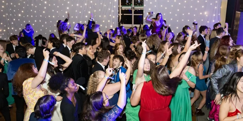 A large group of students wearing evening dress and dancing as a group