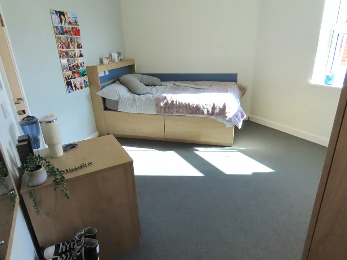 A view of a bed in aa student bedroom .
