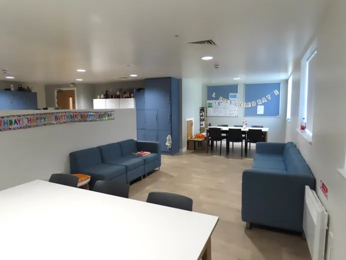 A view of the dining table space and sofa areas within a shared kitchen.
