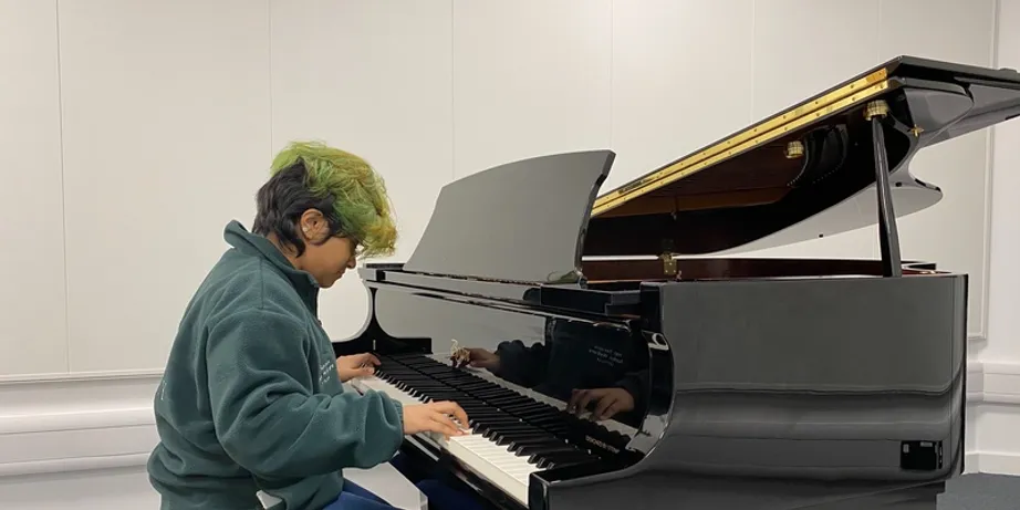 A student playing a baby grand piano